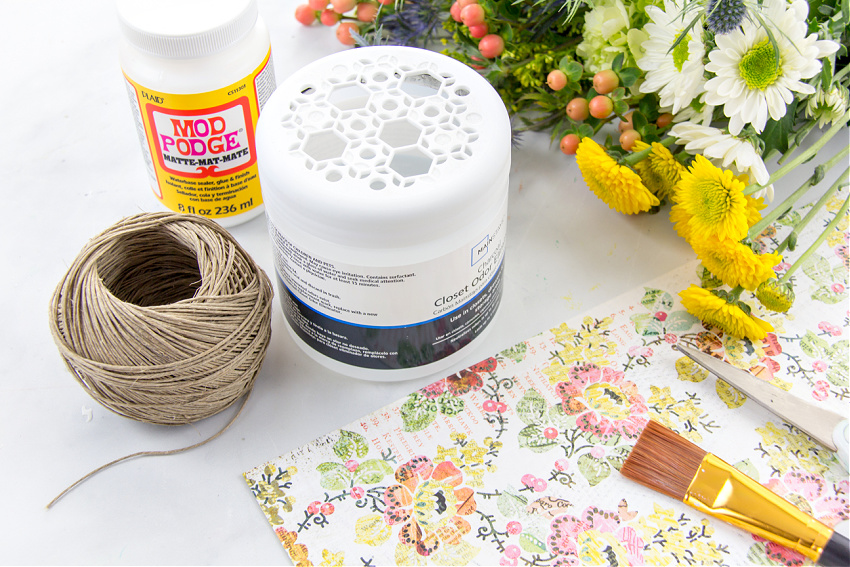 you need a plastic odor eliminator container, scrapbook paper, and mod podge to make a diy vase