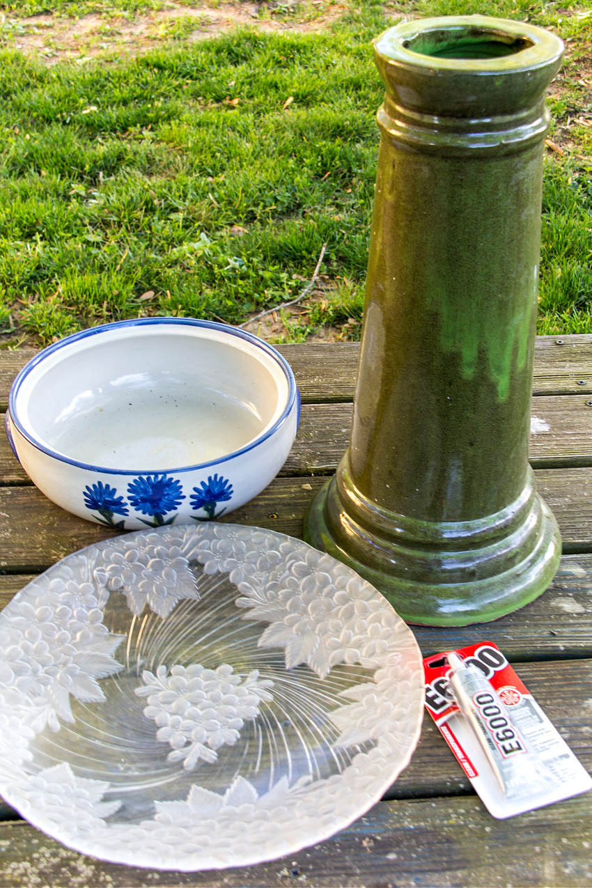 a bird bath base, a large bowl, and a large glass tray to make a diy bird bath