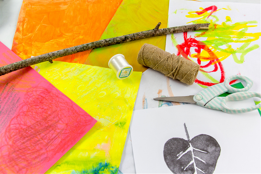 father children's artwork, scissors, a stick, and fishing line to make fall wall decor using children's art.