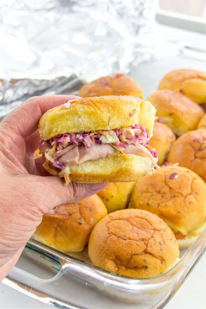turkey and cheese sliders topped with mango coleslaw and baked in an oven dish for a potluck