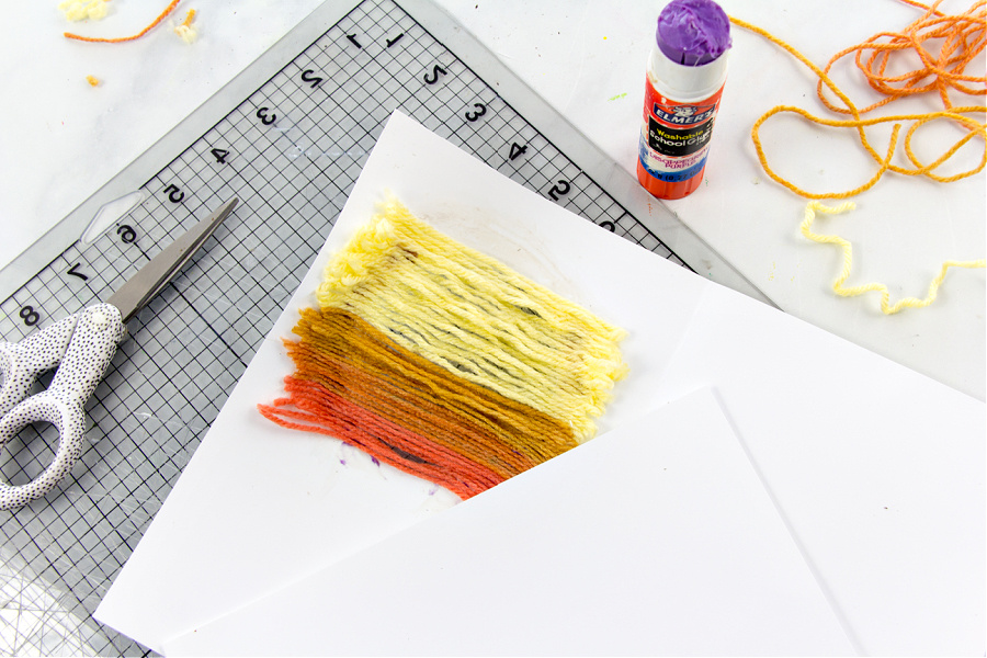 yellow and orange yarn scraps glued over a hole in a greeting card to make the sun